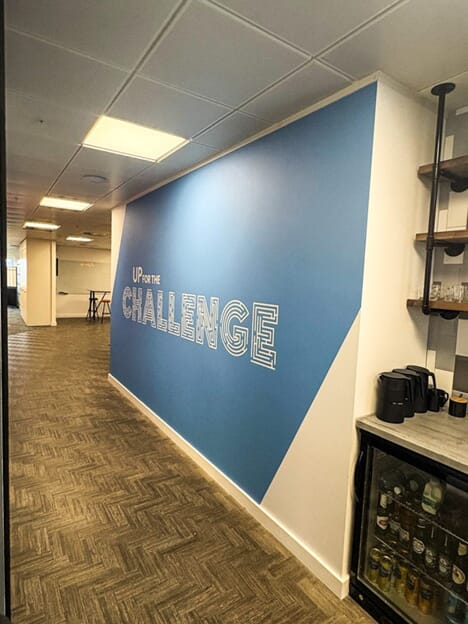 An image of the "Up for the Challenge" blue wall graphic.
